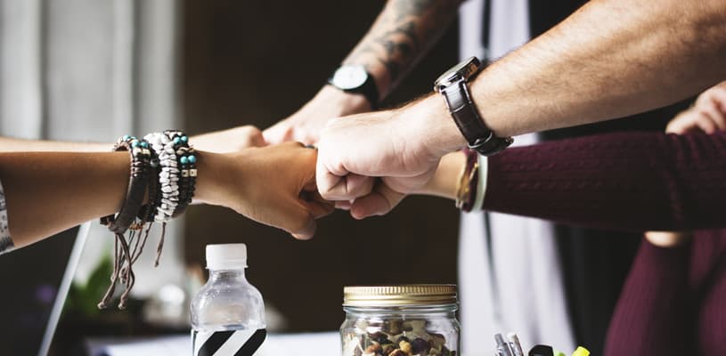 Equipo uniendo manos como símbolo de colaboración